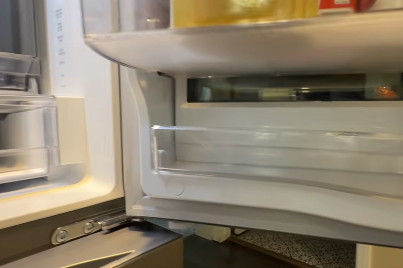 Close-up of refrigerator door shelving and hinge area